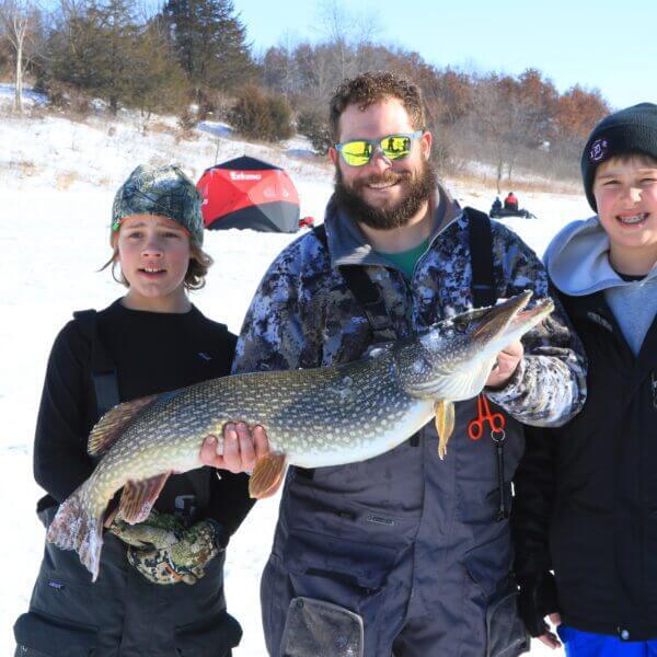 Anglers hold up a northern pike at the ice fishing derby.