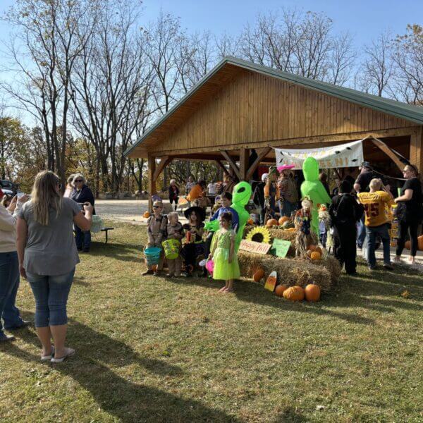Trick-or-treaters pose in costume at the photo booth outside the decorated campground shelter at Lake Meyer during the Trunk or Treat event